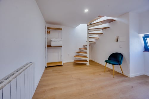 Quarto de loft moderno na Arrabia Guest Houses com escada caracol, pisos de madeira e decoração minimalista em Castelo de Paiva,
