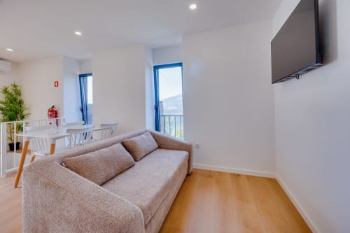 Sala de estar moderna com sofá bege e televisão na Arrabia Guest Houses em Castelo de Paiva, Portugal