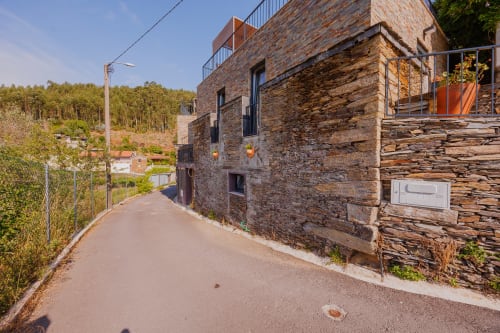 Caminho exterior das Casas de Hóspedes Arrabia em Castelo de Paiva, Portugal, apresentando edifício de pedra restaurado com terraço e