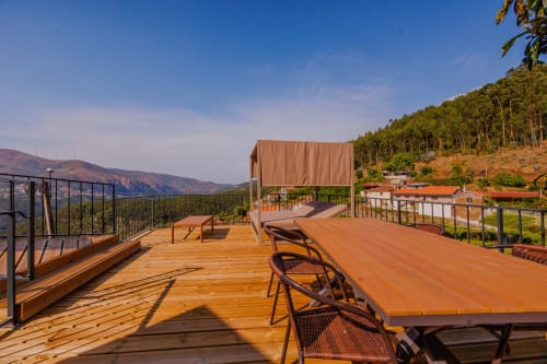 Amplo deck de madeira em Arrabia Guest Houses com vista para montanhas, espreguiçadeiras e área de refeições com vista para a paisagem florestal