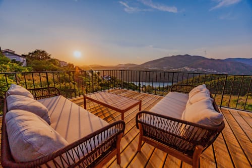 Terraço ao pôr do sol das Arrabia Guest Houses com assentos acolchoados com vista para o vale do rio Raiva, Portugal