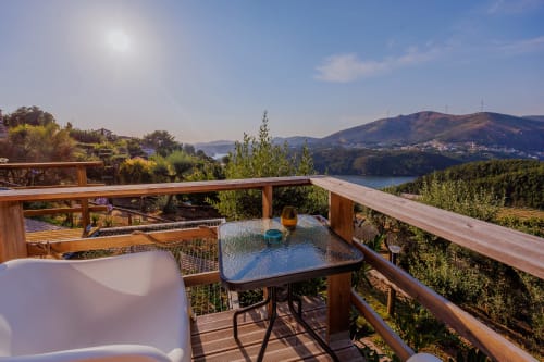 Terraço em madeira nas Casas de Hóspedes Arrabia com mesa, cadeiras, vista para o rio, montanhas e sol em Castelo de Paiva