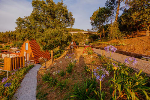 Cabana de glamping nas Casas de Hóspedes Arrabia com flores roxas, caminhos de madeira e vista para o rio em Castelo de Paiva