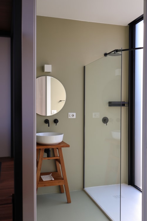 Bagno moderno della Quercia Private Nature Retreat con specchio rotondo, lavabo in ceramica bianca su base in legno e doccia con divisorio in vetro