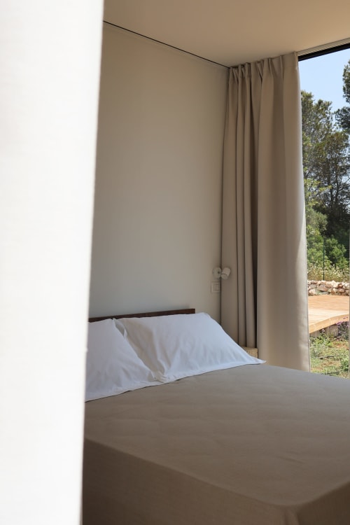 Camera da letto minimalista con cuscino bianco e tende beige presso Quercia Private Nature Retreat, Maglie Italia