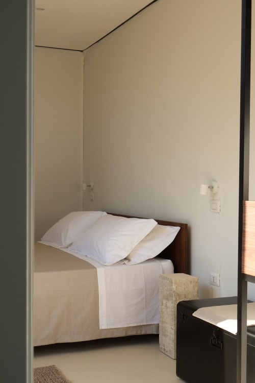 Camera da letto minimalista a Quercia Private Nature Retreat a Maglie con cuscini bianchi, biancheria neutra e accento in pietra moderna