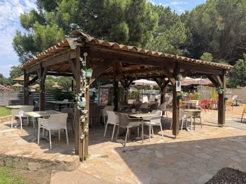 Pergola en bois avec coin repas à Tamaricciu Di Cala Rossa à Lecci, chaises blanches et pins méditerranéens