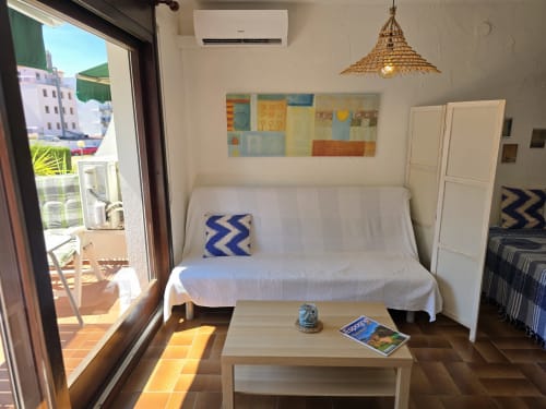 Studio cosy à Roses avec canapé blanc, vue sur la terrasse et équipements modernes près de la plage