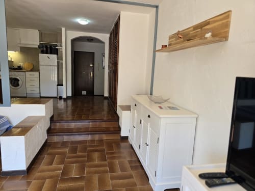 Couloir confortable d'un studio à Roses avec carrelage en terre cuite, mobilier blanc et accès à la cuisine