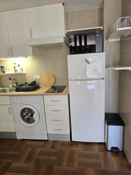 Cuisine studio moderne avec lave-linge, réfrigérateur blanc, micro-ondes et cuisinière dans un appartement à Roses près de la plage