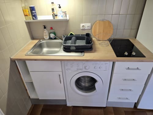 Kitchenette d'un appartement en front de mer à Roses avec évier, cuisinière, lave-linge et égouttoir