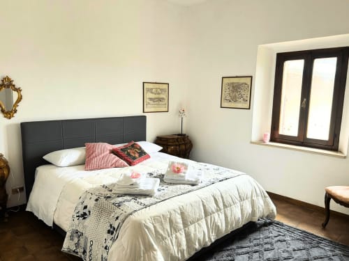 Camera da letto a Torre Della Chiocciola B&B a Monteriggioni con letto matrimoniale, testata nera e finestre con vista su Siena