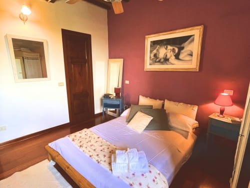 Camera accogliente alla Torre Della Chiocciola B&B di Monteriggioni con pareti bordeaux, letto in legno e illuminazione calda