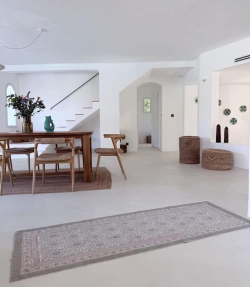 Spacieuse villa ouverte à Grasse avec table en bois, mobilier tressé, murs blancs et escalier