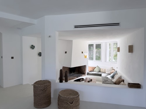 Salon moderne de villa avec foyer, poufs tressés et coin salon baigné de soleil avec vue sur les montagnes à Grasse