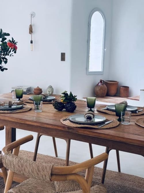 Élégante salle à manger à la villa RJD Conciergerie à Grasse avec table en bois, chaises tissées, verrerie verte et terre cuite