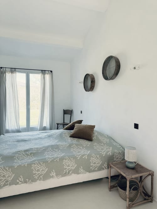 Chambre lumineuse de villa à Grasse avec linge de lit motifs, vue montagne par portes vitrées et touches décor rustique