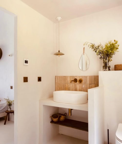 Salle de bain de villa moderne à Grasse avec vasque blanche, carrelage bois au mur, luminaire suspendu et plantes décoratives