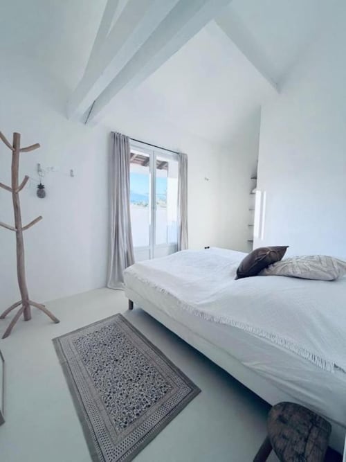 Chambre minimaliste blanche avec vue montagne, portemanteau bois et grand lit à la villa RJD Conciergerie Côte d'Azur à Grasse