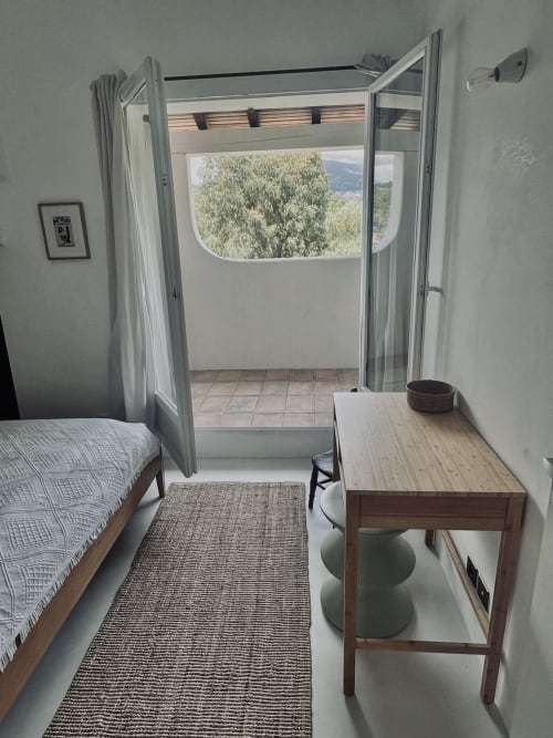 Chambre lumineuse de villa à Grasse avec lit, bureau et portes ouvertes sur vue montagne et terrasse aux oliviers