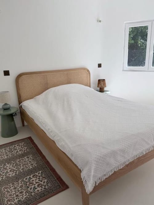 Chambre minimaliste avec tête de lit en rotin naturel, literie blanche et vue sur la verdure à la villa RJD Conciergerie