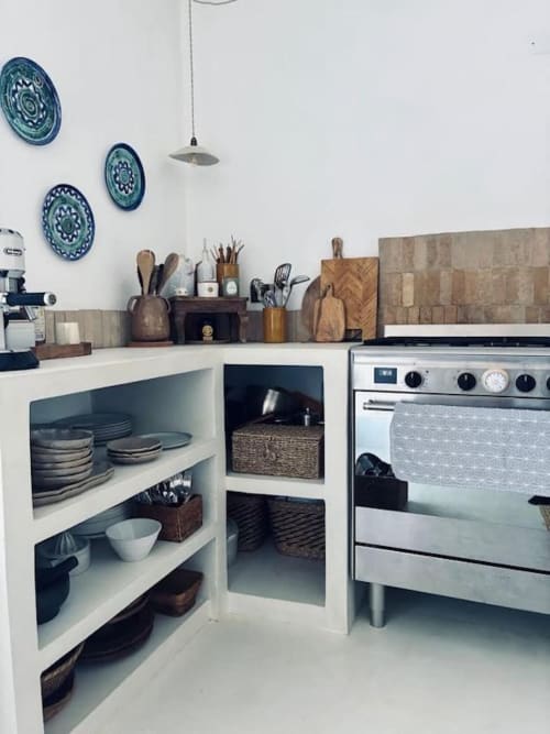 Cuisine de villa moderne à Grasse avec étagères blanches, four inox, ustensiles en bois et assiettes décoratives bleues