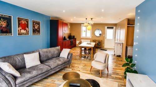 Élégant salon de villa moderne à Ô de Mer avec murs bleus, canapé gris, table en bois et cuisine à Sangatte