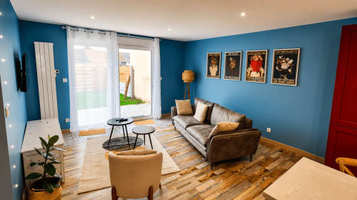 Salon moderne de la villa Ô de Mer à Sangatte avec murs bleus, canapé en cuir et accès à la vue sur jardin