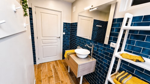 Salle de bains moderne à la villa Ô de Mer à Sangatte avec carrelage bleu métro, meuble vasque en bois et serviettes jaunes