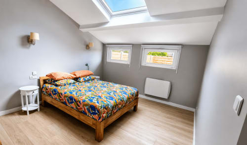 Chambre lumineuse de la villa Maison Ô de Vents à Sangatte, avec lit en bois, puits de lumière et vue sur le jardin côtier