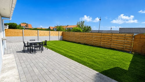 Spacieux jardin avec terrasse, pelouse et clôture en bois à la villa Maison Ô de Vents à Sangatte