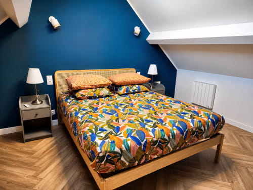 Chambre de la villa Ô de Mer près de la plage de Sangatte, avec linge de lit coloré à motifs, lit en bois, tête de lit en rotin