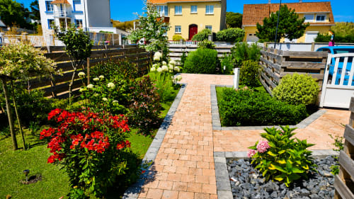 Jardin de la villa Maison Ô Gris-Nez avec allée en briques, fleurs rouges et haies près de la plage de Sangatte