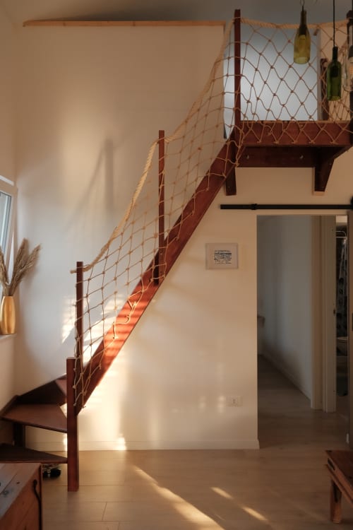Modern apartment interior at WelcHome in Rocca San Giovanni with red metal staircase, rope railing, and minimalist design