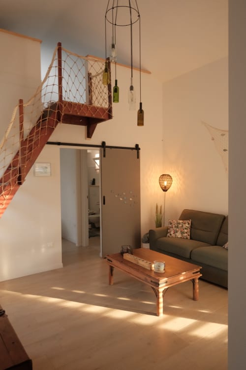 Modern loft apartment at WelcHome in Rocca San Giovanni with mezzanine, sofa, wooden table, and hanging bottle lights