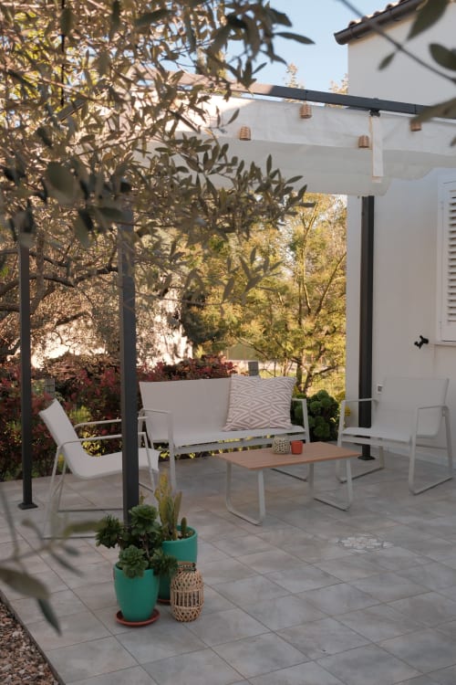 Modern patio with pergola, white seating, wooden table, and olive trees at Casa Verde Oliva apartment in Rocca San Giovanni