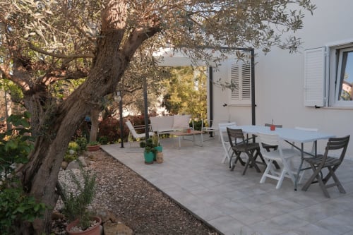 Outdoor dining terrace at Casa Verde Oliva with ancient olive tree, white furniture, and sea view in Rocca San Giovanni