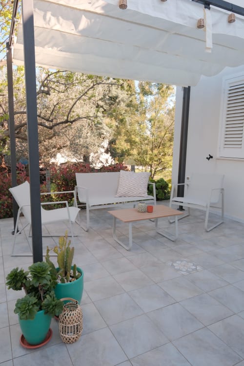 Modern patio at WelcHome Casa Verde Oliva with white furniture, pergola shade, and garden view in Rocca San Giovanni