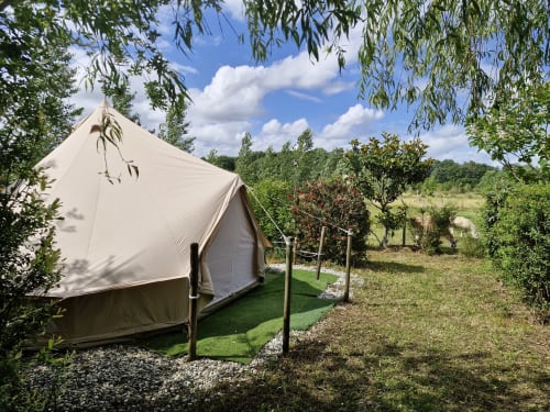 Tente de glamping à La Petite Ferme De Pouillon entourée de jardins verdoyants, d'arbres et de ciel bleu à Pouillon, France