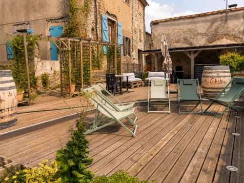 Terrace at Au Château De Villelongue with wooden deck, lounge chairs, and ivy-covered stone buildings in Villelongue-dʼAude