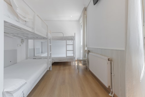 Limpia habitación compartida con cuatro literas, piso de madera y ventanas en Hostal Costa Coruña, A Coruña