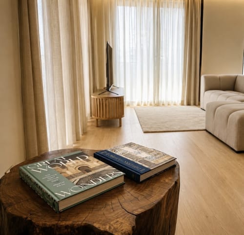 Sala de estar de apartamento de luxo com livros sobre mesa de madeira, móveis creme e vista para o oceano na Terra Clara Studio