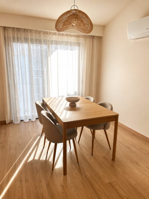 Sala de jantar brilhante no Apartamento Atlântico da Terra Clara com mesa de madeira, luminária de fibra trançada e vistas do oceano