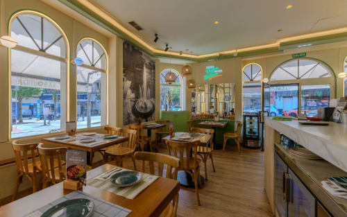 Comedor del Hostal Costa Coruña con mesas y sillas de madera, amplios ventanales con vistas a la calle de A Coruña