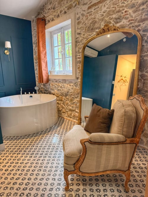 Salle de bain de la Suite Gîte luxueuse à la Bastide la Mourelette, Toulon, avec murs en pierre, baignoire ilôt, miroir ouvragé