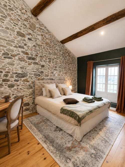 Chambre de luxe à la Bastide la Mourelette à Toulon avec murs en pierre, poutres en bois et confort moderne