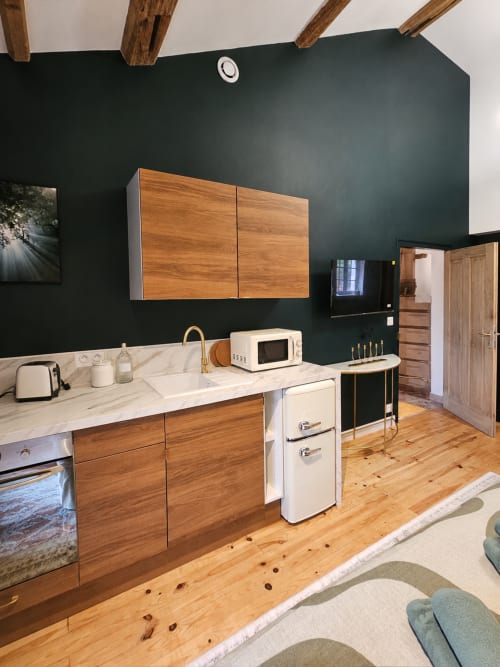 Cuisine moderne aux murs vert foncé, boiseries, plan de travail en marbre et appareils inox chez Bastide la
