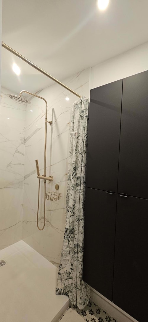 Salle de bain moderne avec douche pluie, carrelage marbre, rideau de douche botanique et meuble noir au Gîte Bastide la Mourelette