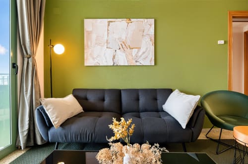 Sala de estar moderna con sofá negro, paredes verde lima y arte abstracto cerca de la playa de Valencia