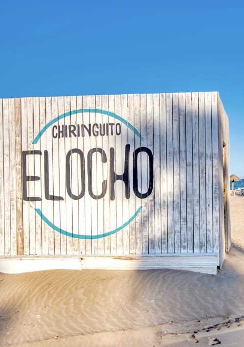 Chiringuito Elocho, chiringuito en la playa de Valencia con estructura de madera blanca y señalización turquesa